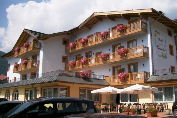 Trzypiętrowy hotel z drewnianymi balkonami ozdobionymi kwiatami.