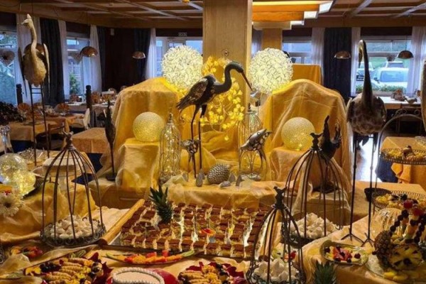 Luksusowo ozdobiony stół z deserami i dekoracjami w złotych tonach oraz figurkami ptaków w eleganckiej jadalni.