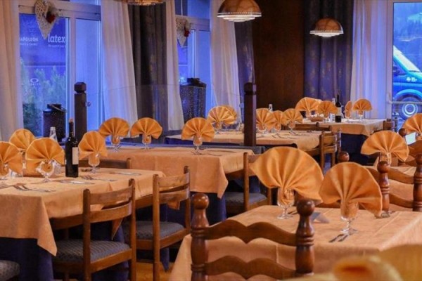 Elegancko udekorowana restauracja z drewnianymi stołami i krzesłami oraz złożonymi pomarańczowymi serwetkami.
