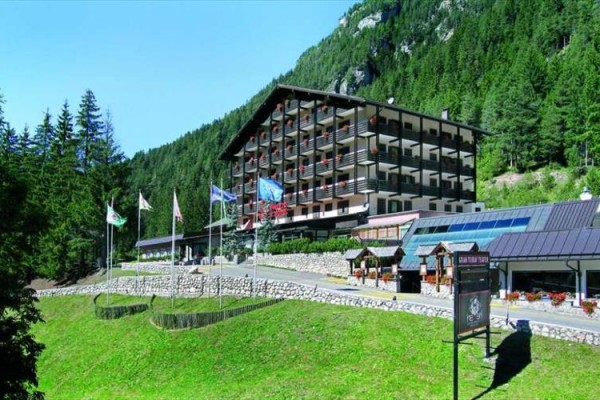 Hotel otoczony zielonymi lasami w górskim krajobrazie.
