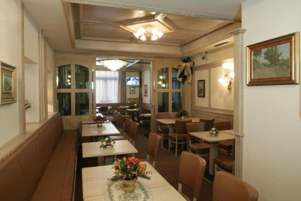 Wnętrze restauracji z drewnianymi stołami i krzesłami, ozdobione kwiatami.