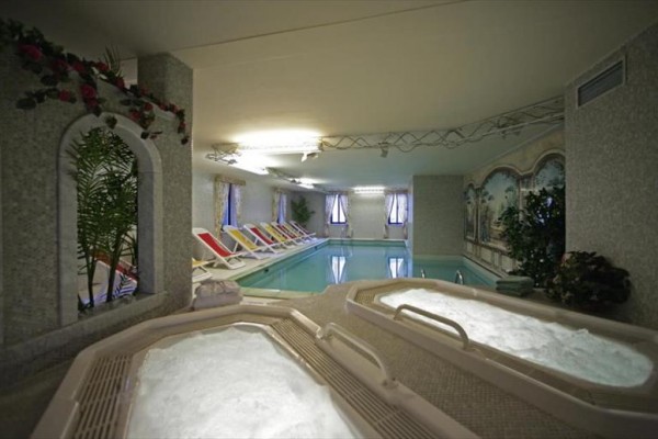 Kryty basen z jacuzzi i leżakami do relaksu.
