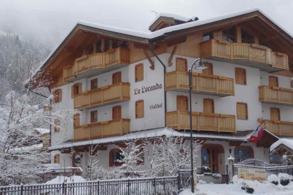 Górski hotel z drewnianymi balkonami pokryty śniegiem w zimowym krajobrazie.