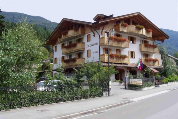 Trzypiętrowy hotel z drewnianymi balkonami i kwiatami na krawędziach balkonów.