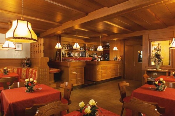 Wnętrze restauracji z drewnianymi meblami i czerwonymi obrusami.