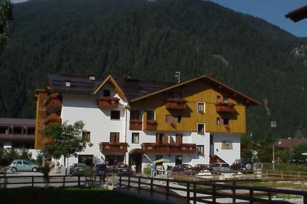 Budynek hotelowy z drewnianymi balkonami przed lasem i górą.