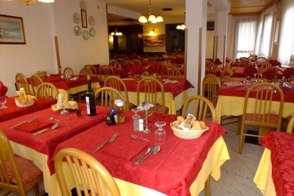 Restauracja z drewnianymi krzesłami i stołami z czerwonymi obrusami.