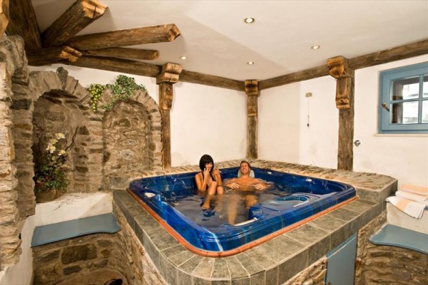 Para relaksująca w jacuzzi w rustykalnym pomieszczeniu z kamiennymi ścianami.