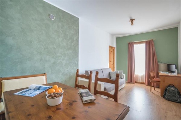 Jasny salon z drewnianym stołem, kanapą i zielonymi ścianami.