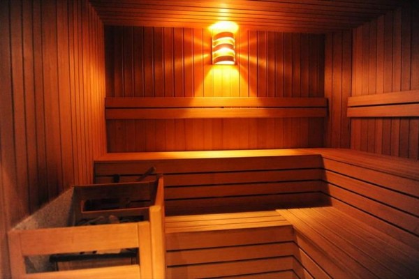 Drewniana sauna z ławkami i delikatnym oświetleniem na ścianie.