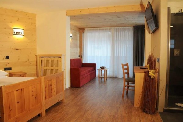 Nowoczesny pokój hotelowy z drewnianymi meblami i czerwoną sofą.
