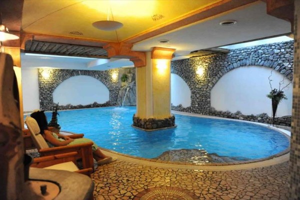 Wnętrze basenu spa z kamiennymi ścianami i fotelem.