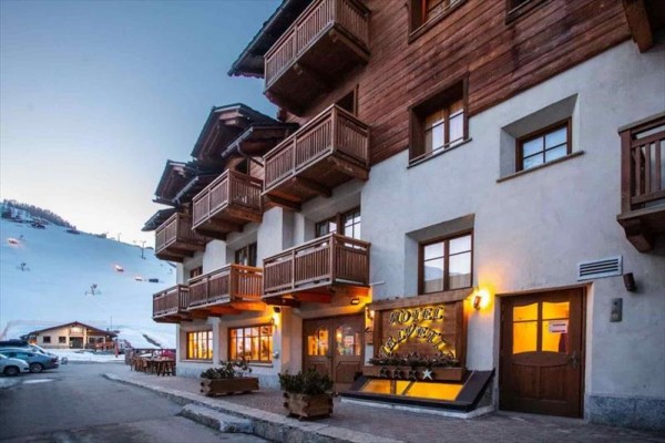 Hotel z drewnianymi balkonami przy ośnieżonym stoku o zmierzchu.