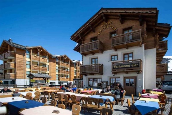 Drewniany hotel z restauracją i miejscami do siedzenia na zewnątrz.
