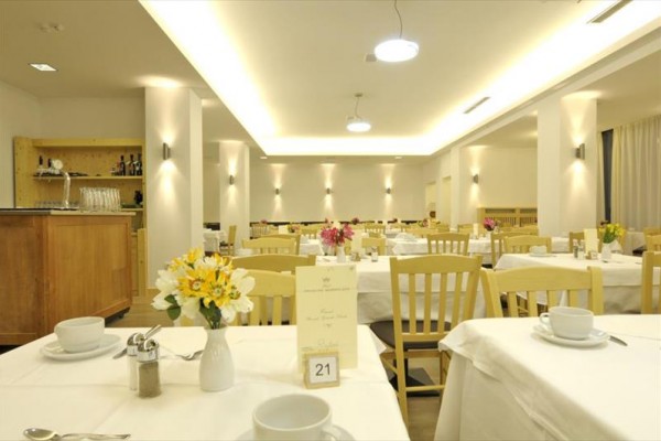 Jasna restauracja z nakrytymi stołami i dekoracjami z kwiatów.