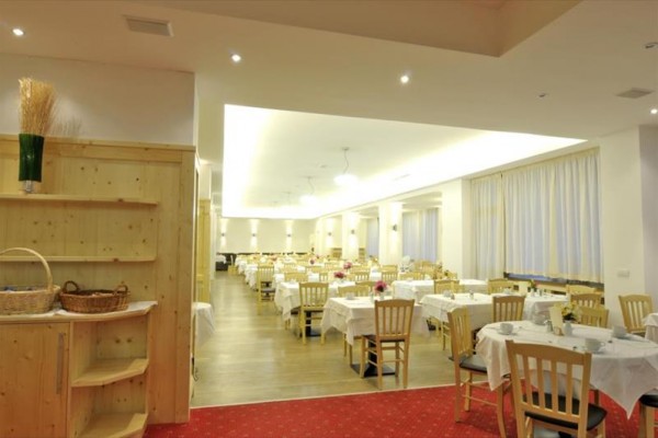 Recepcja hotelowa z czerwonym dywanem, drewnianym blatem i kamiennymi słupami.