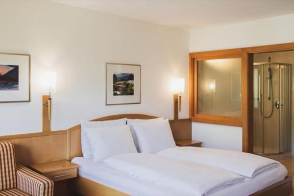 Nowoczesny pokój hotelowy z podwójnym łóżkiem i kabiną prysznicową.