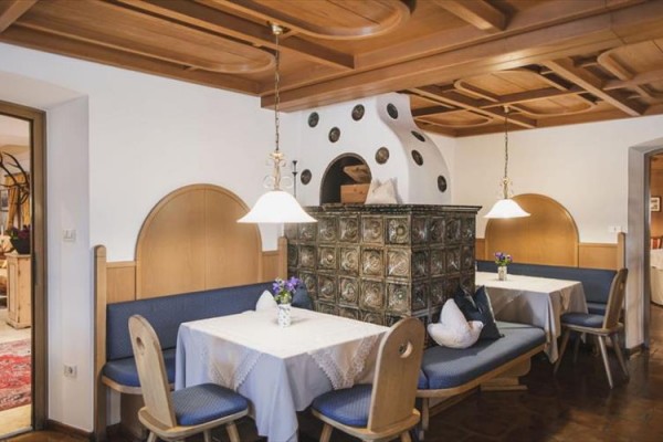 Restauracja z drewnianą boazerią i tradycyjnym piecem kaflowym na środku pomieszczenia.