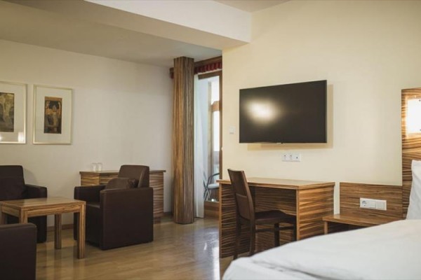 Nowoczesny pokój hotelowy z drewnianymi meblami i telewizorem na ścianie.
