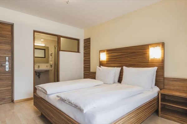 Nowoczesny pokój hotelowy z łóżkiem małżeńskim obok łazienki.