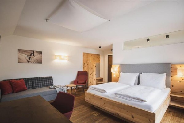 Nowoczesny pokój hotelowy z podwójnym łóżkiem, sofą i drewnianymi meblami.