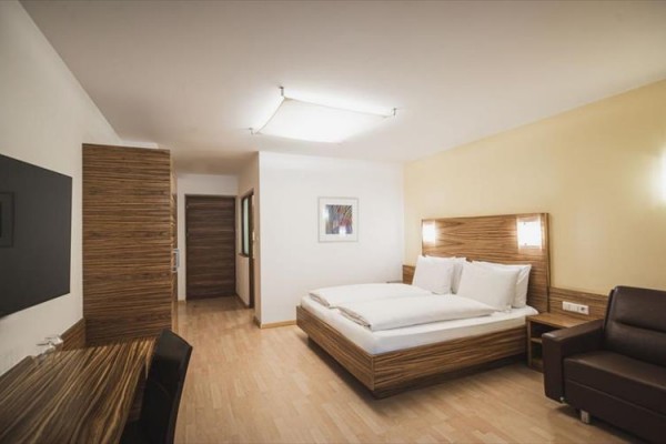Nowoczesny pokój hotelowy z łóżkiem małżeńskim, biurkiem i sofą.
