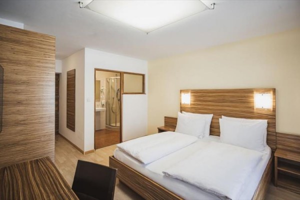 Nowoczesny pokój hotelowy z podwójnym łóżkiem, drewnianymi meblami i łazienką.