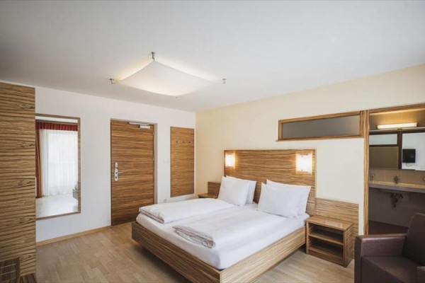 Nowocześnie urządzony pokój hotelowy z łóżkiem dwuosobowym i drewnianymi meblami.