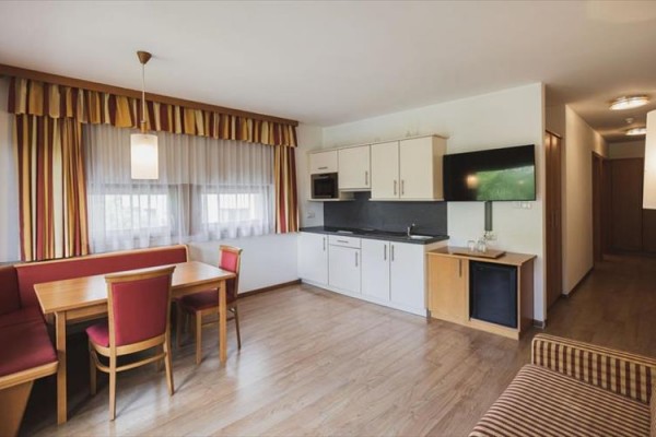 Aneks kuchenny w apartamencie z jadalnianym stołem i czterema krzesłami.