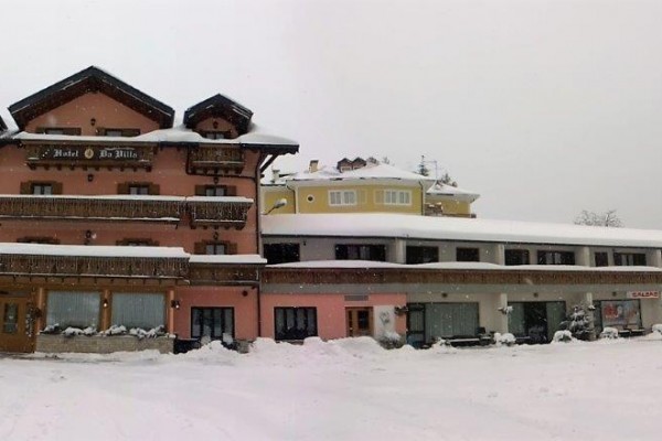Wnętrze restauracji z dekoracjami w stylu drewna i kamienia, na ścianie duża czarno-biała fotografia gór.