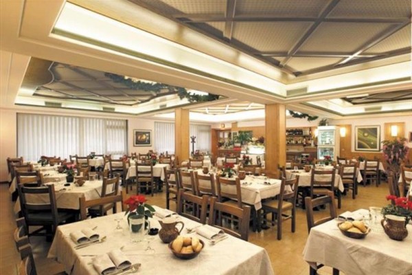 Restauracja z drewnianym sufitem i zdjęciem ośnieżonych gór na ścianie.