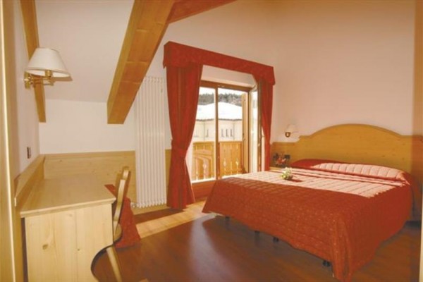 Różowy hotel z drewnianymi balkonami pokrytymi śniegiem.