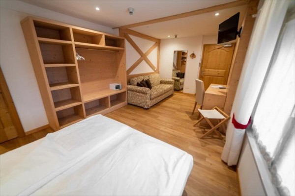 Nowoczesny pokój hotelowy z drewnianymi meblami, łóżkiem, sofą i biurkiem.