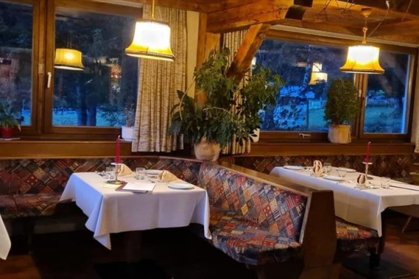 Restauracja z drewnianymi ławkami i nakrytymi stolami przy oknie z widokiem na naturę.  