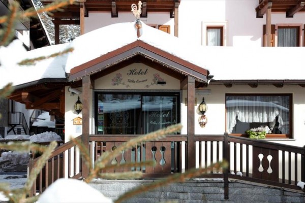 Wejście do ośnieżonego hotelu z drewnianą balustradą.