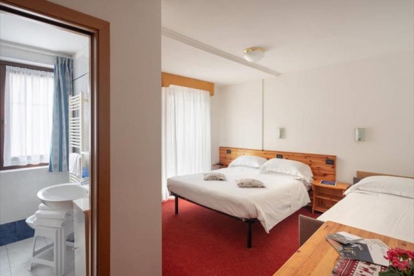 Przytulny pokój hotelowy z łóżkiem małżeńskim i przyległą łazienką.