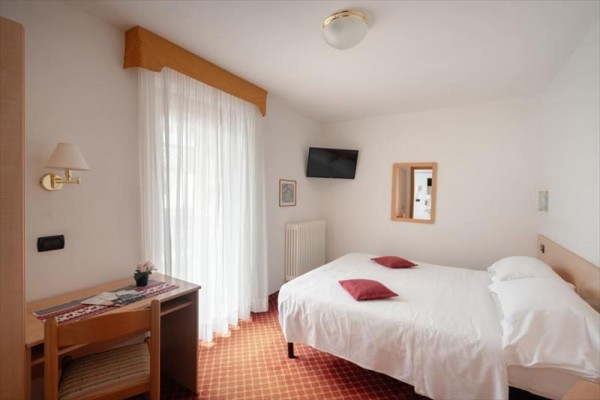 Prosty pokój hotelowy z podwójnym łóżkiem, telewizorem i stołem.