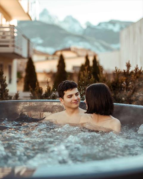 Para w jacuzzi z górami w tle.