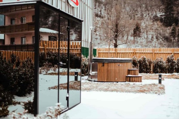 Ogród z sauną i jacuzzi pokryty cienką warstwą śniegu.