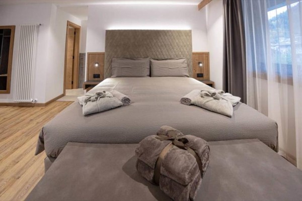 Pokój hotelowy z łóżkiem małżeńskim, na którym leżą złożone ręczniki.