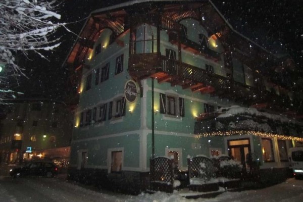 Zaśnieżony hotel w nocy z oświetloną fasadą.