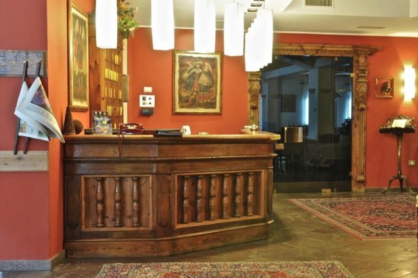 Recepcja hotelowa z drewnianym blatem i orientalnymi dywanami.