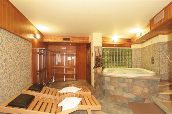 Pokój wellness z jacuzzi, leżakami i drewnianym wykończeniem.