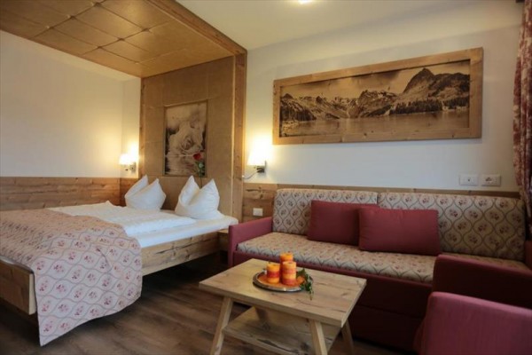 Stylowy pokój hotelowy z drewnianym wystrojem, łóżkiem małżeńskim i sofą.