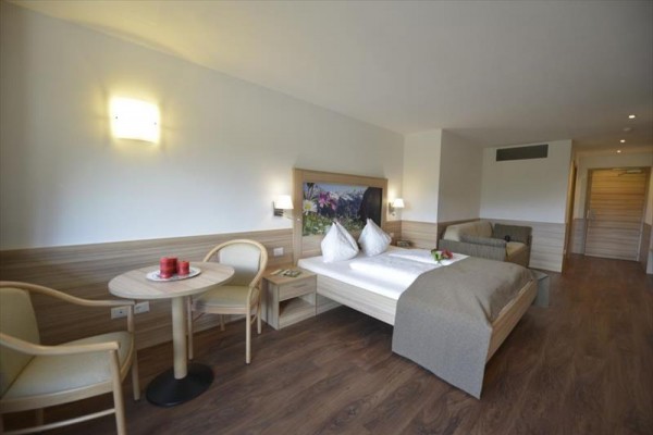 Nowoczesny pokój hotelowy z podwójnym łóżkiem, sofą i okrągłym stołem.