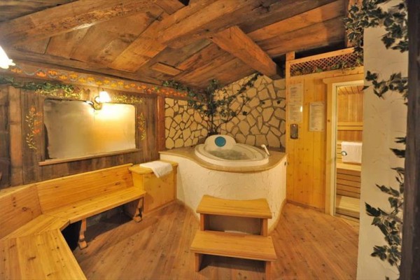 Przytulna drewniana sauna z jacuzzi i miejscem do siedzenia w rustykalnym stylu.