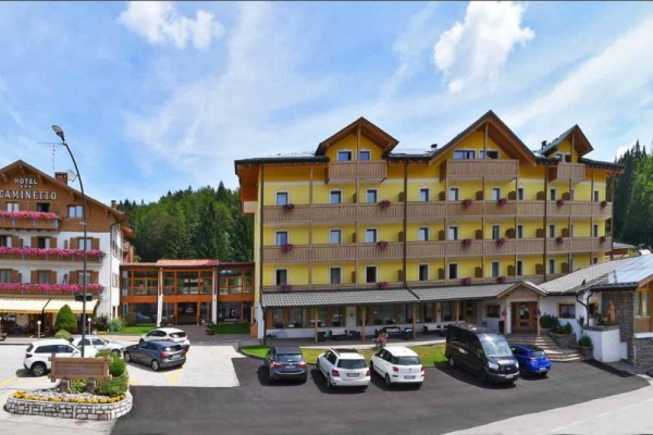 Duży kompleks hotelowy z parkingiem otoczony przyrodą.