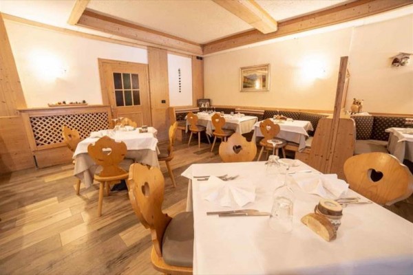 Restauracja z drewnianymi meblami i nakrytymi stołami.