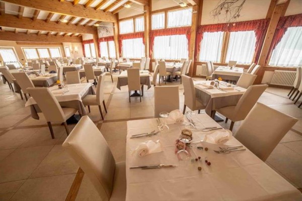 Przestronna restauracja z białymi obrusami i wygodnymi krzesłami.