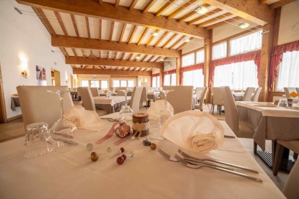 Restauracja z nakrytymi stołami i drewnianym sufitem.